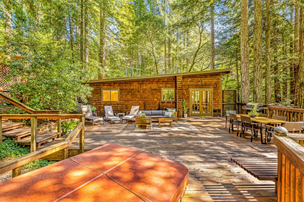 a log cabin in the woods with tables and chairs at Tree Tops Bungalow in Guerneville