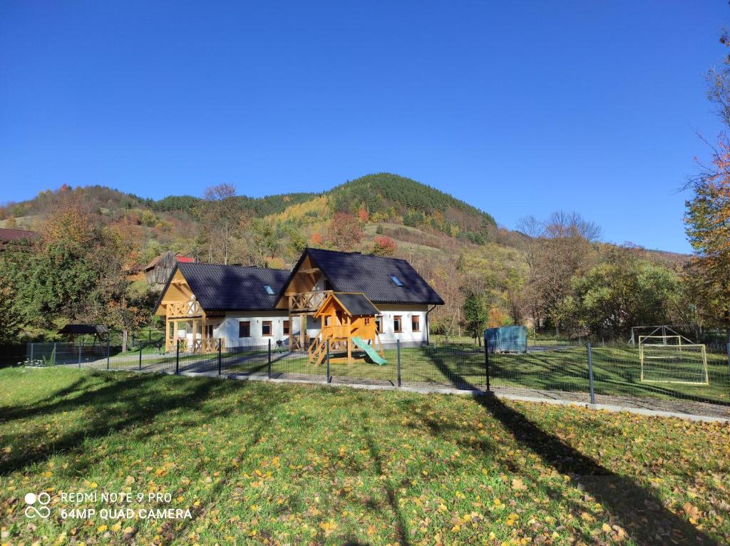 une maison avec une aire de jeux en face d'un champ dans l'établissement Domki Pod Brzyzkiem, à Ochotnica Dolna