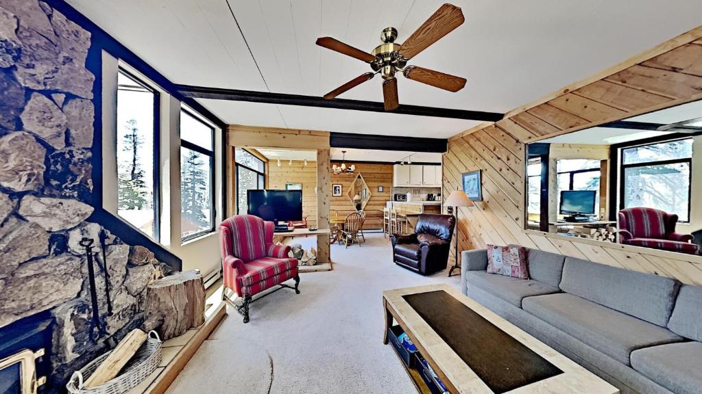 ein Wohnzimmer mit einem Deckenventilator und einer Steinmauer in der Unterkunft Two Bedroom Units at 1849 Condos with 3 Hot Tubs & Slopeside in Mammoth Lakes