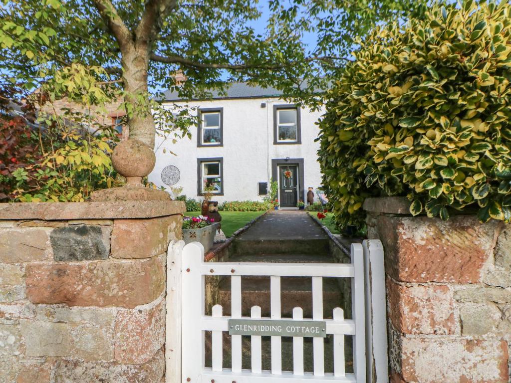 a white gate in front of a white house at Glenridding Cottage in Warcop