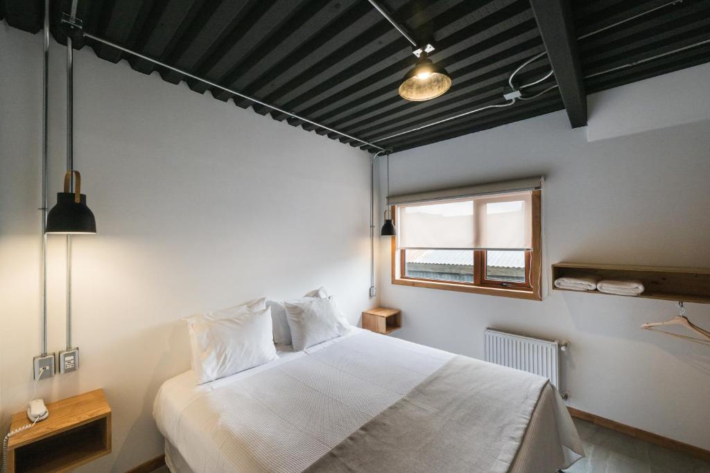 a bedroom with a white bed and a window at Hotel Big Sur in Puerto Natales