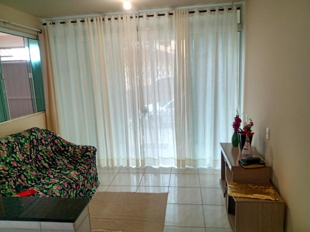 - un salon avec un canapé et une grande fenêtre dans l'établissement Casa a 40 metros da praia, à Governador Celso Ramos