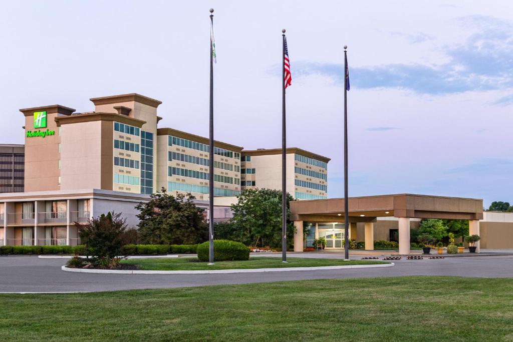 a hotel with two flags in front of a building at Holiday Inn Louisville East - Hurstbourne by IHG in Louisville