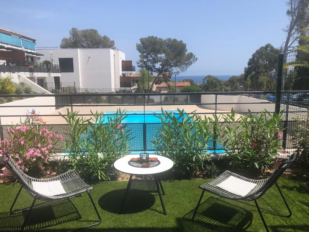 a patio with three chairs and a table and a pool at Superbe Appartement T2 avec Piscine et Vue Mer in Fréjus