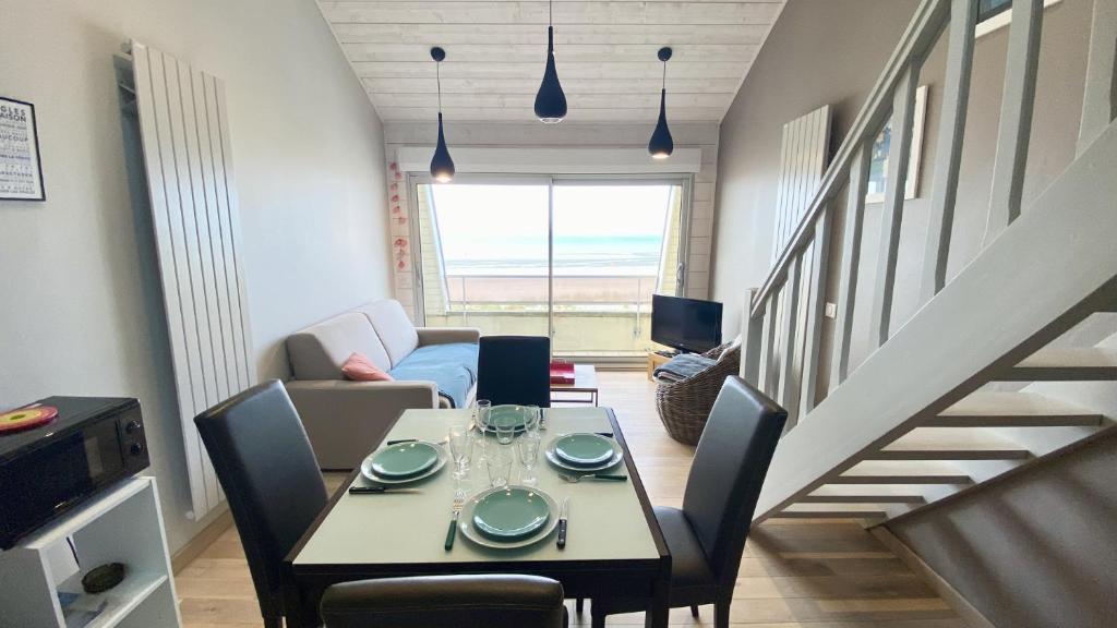 salon ze stołem i krzesłami oraz schodami w obiekcie Appartement vue mer, Brigantine w mieście Fort-Mahon-Plage
