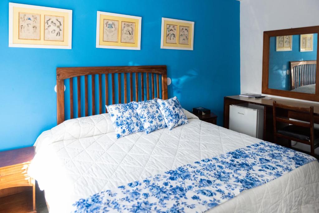 a bedroom with a bed with a blue wall at Mara Palace Hotel in Vassouras
