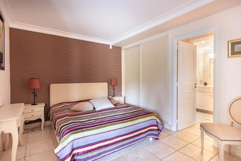 a bedroom with a bed with a colorful striped blanket at VILLA LE MAS D&#39;AZUR BY ESTATESCANNES in Vallauris