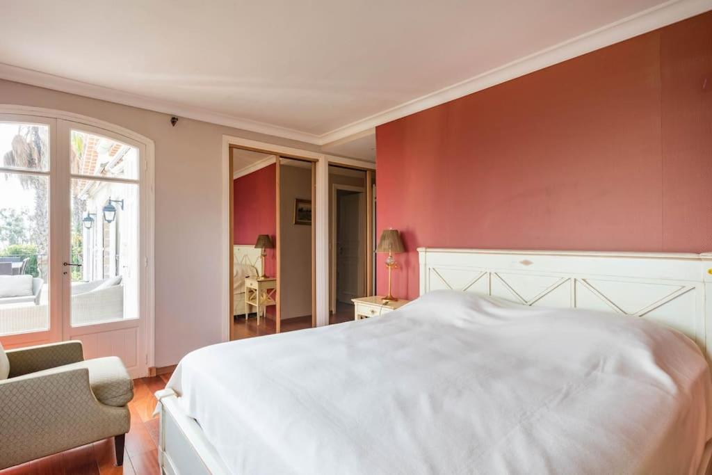 a bedroom with a white bed and a red wall at VILLA LE MAS D&#39;AZUR BY ESTATESCANNES in Vallauris