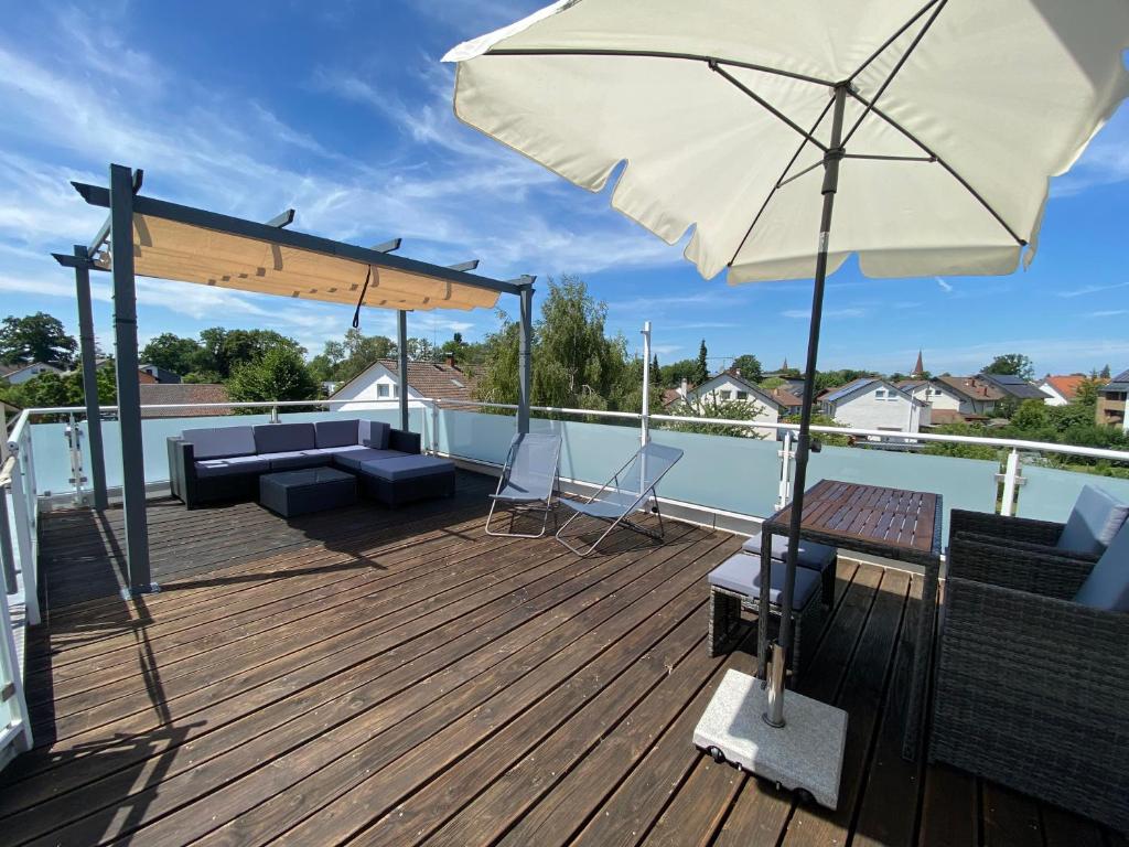 eine Terrasse mit einem Sofa und einem Sonnenschirm in der Unterkunft Apartment Art in Bad Krozingen
