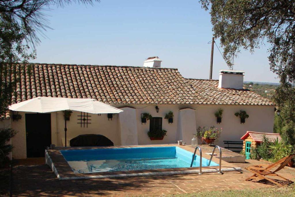 a house with a swimming pool and an umbrella at Casa das Moles in Évora