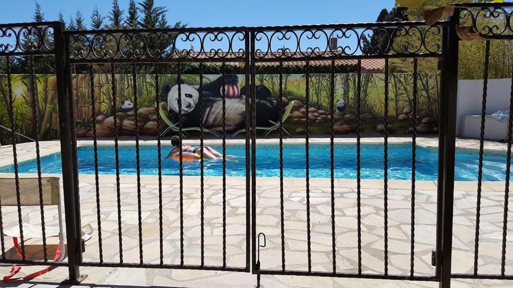 a gate with a panda bear laying next to a pool at Tranquillité B&B in Cuxac-dʼAude