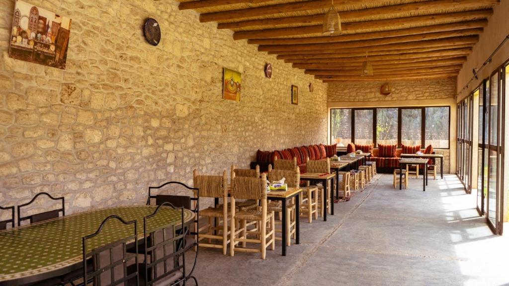 Dar Ayman Essaouira في الصويرة: غرفة طعام مع طاولات وكراسي ونوافذ