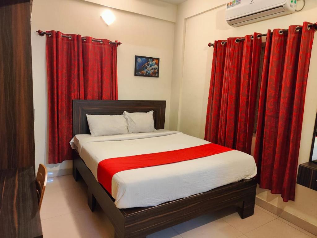 a bedroom with a bed with red curtains at Pristine Inn Manyata in Bangalore