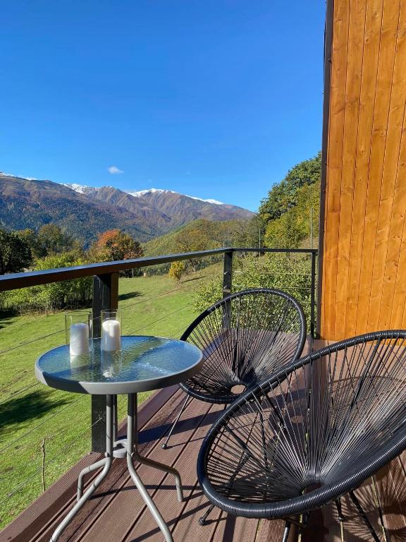 a table and chairs on a deck with mountains in the background at Roots Svaneti &#39; რუთს სვანეთი in Lentekhi