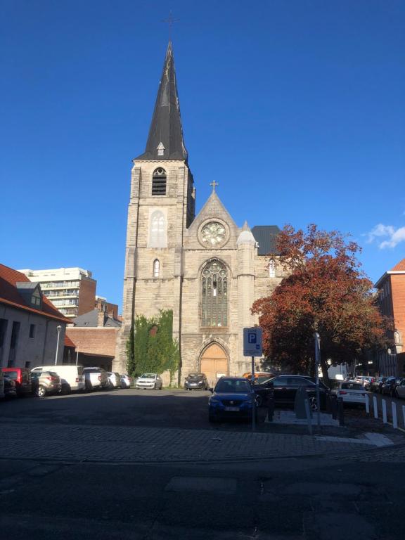 una iglesia con una torre de reloj en un estacionamiento en Appartement centre ville, en Tournai