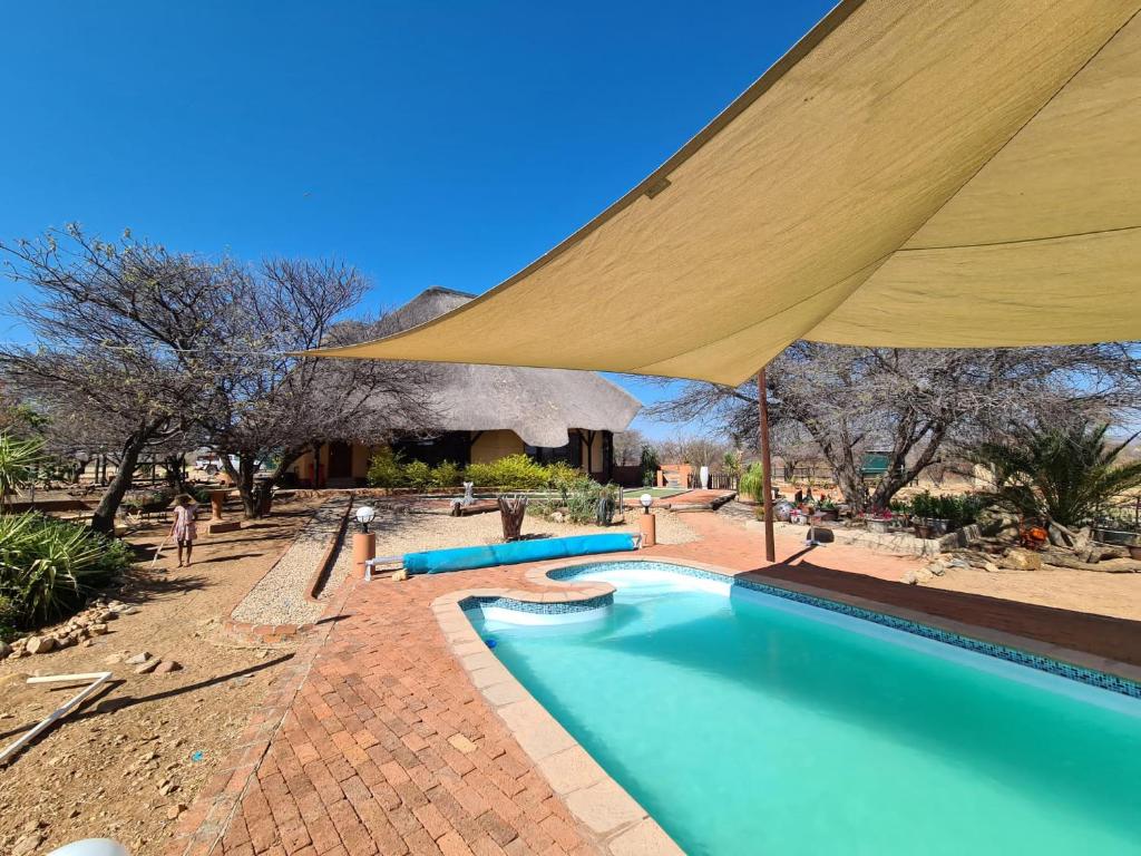 a swimming pool with a large umbrella over it at Privathaus mit eigenem Pool - Windhoek in Windhoek