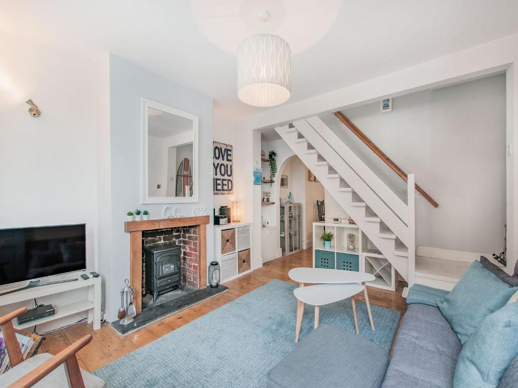 a living room with a staircase and a fireplace at Kiwi Cottage in Whitstable