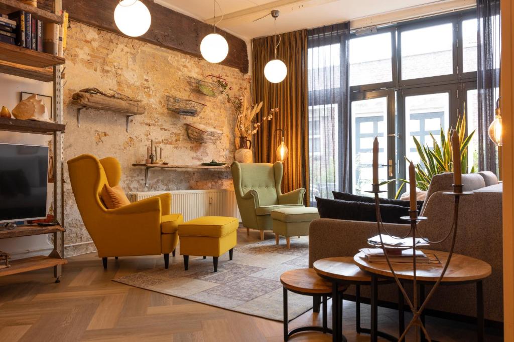 een woonkamer met gele stoelen en een tv bij PASSAGE - historic boutique suite in Haarlem