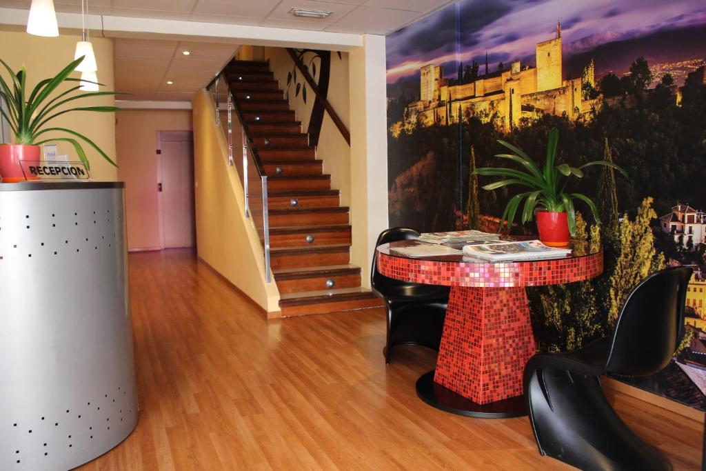 een lobby met een tafel en stoelen en een trap bij Hotel La Curva in Albolote