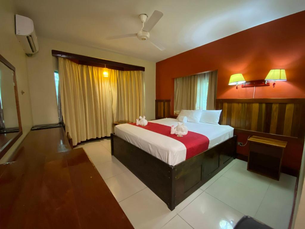 una camera con un letto con una parete rossa di Caye Caulker Plaza Hotel a Caye Caulker