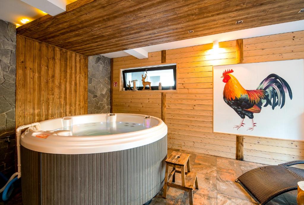 a room with a tub with a rooster on the wall at Loft Apart View & Wellness in Szczyrk
