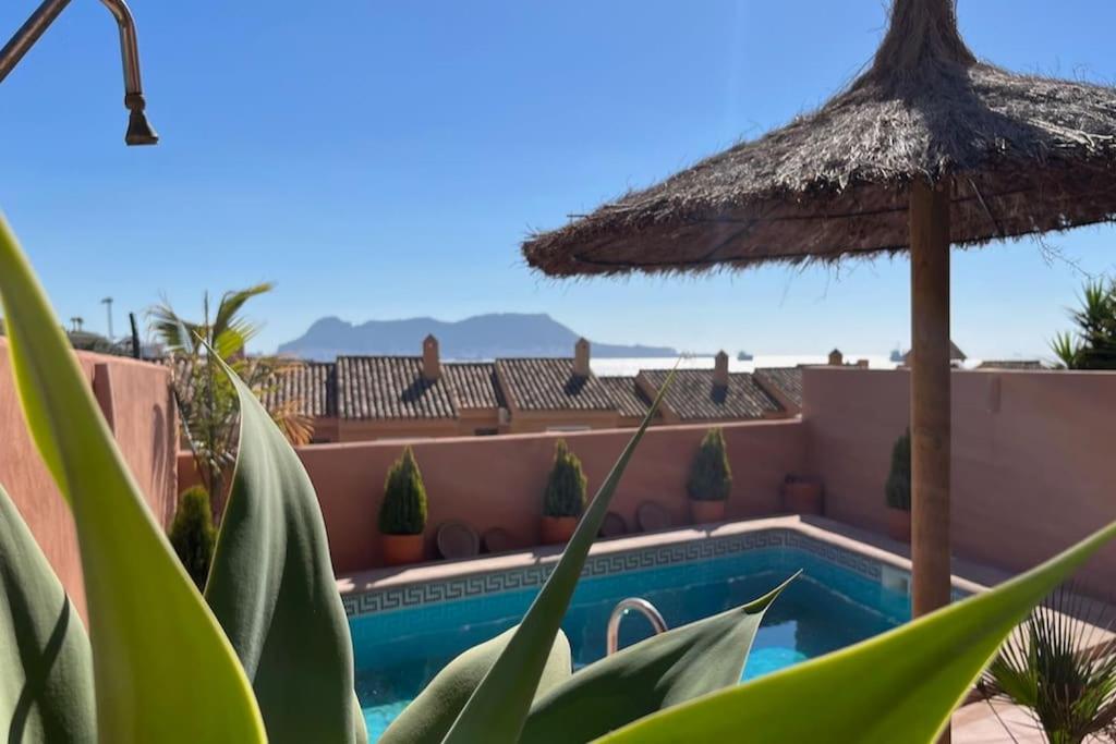 uma villa com uma piscina e um guarda-sol de palha em La Barossa em Algeciras