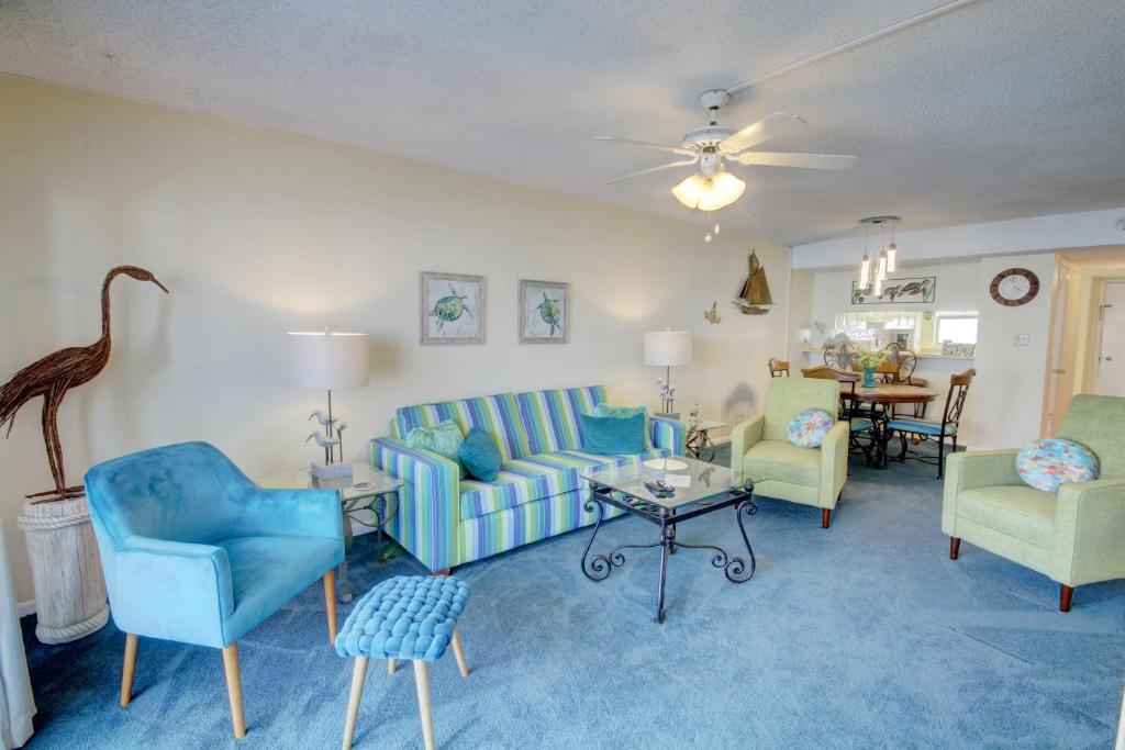 Una sala de estar con un sofá azul y sillas. en El Matador 443 - Beautiful views of the pool and Gulf of Mexico, en Fort Walton Beach