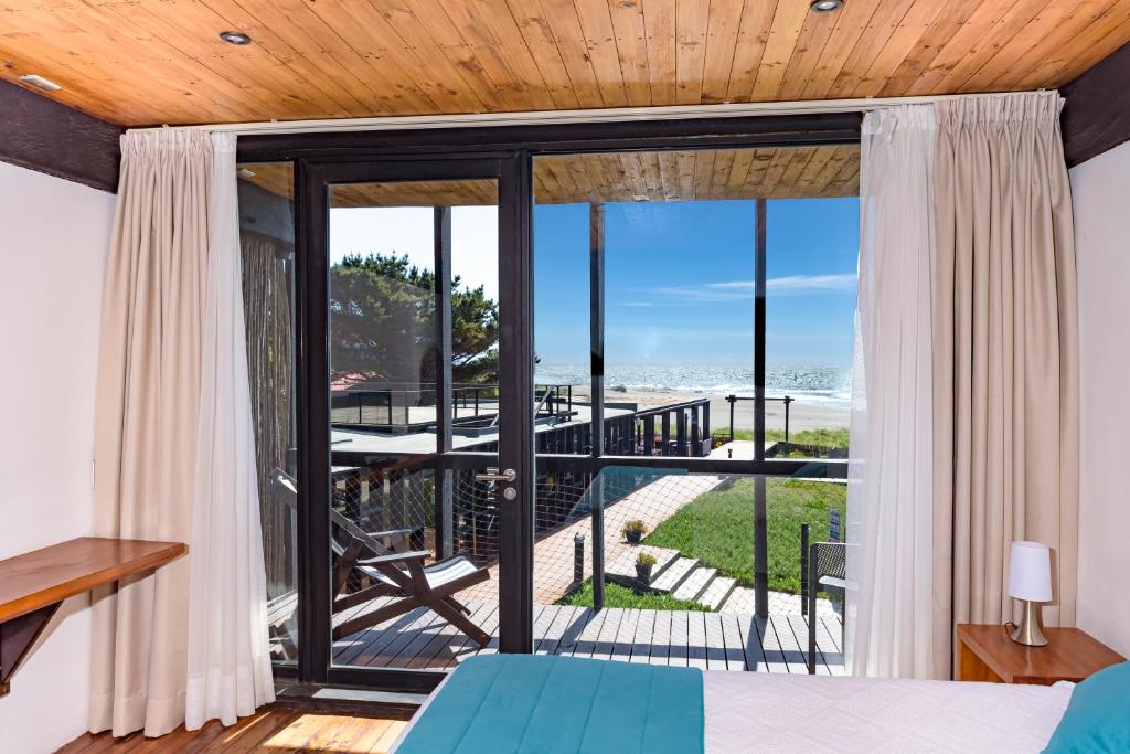 a bedroom with a view of the beach through glass doors at Hotel Punta Sirena in Curanipe