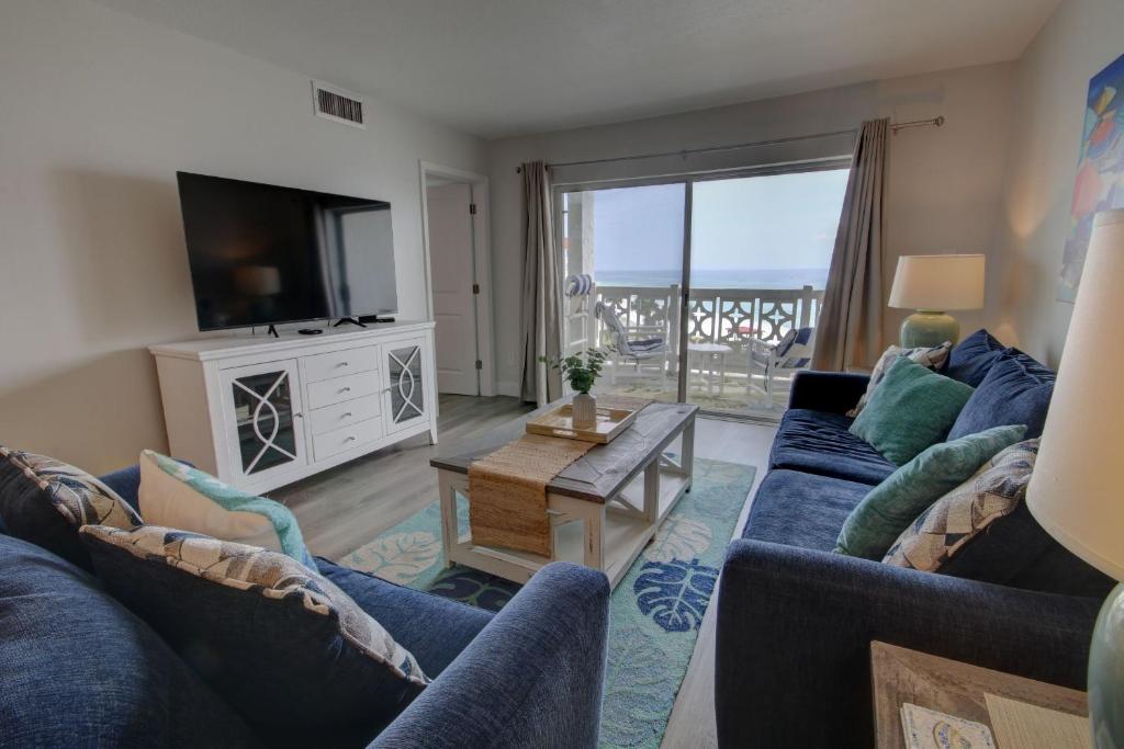 Sala de estar con 2 sofás azules y TV en El Matador 457 - Gulf front with beautiful views of the Gulf and pool, en Fort Walton Beach