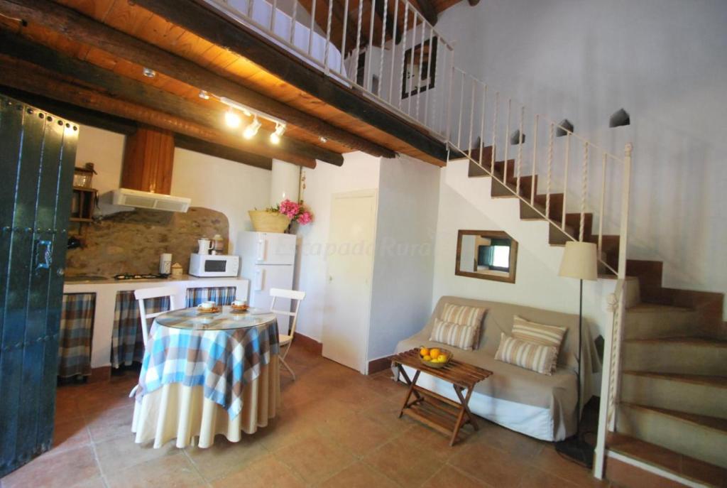 a living room with a table and a kitchen at Finca La Vicaria PALOMAR in Zufre