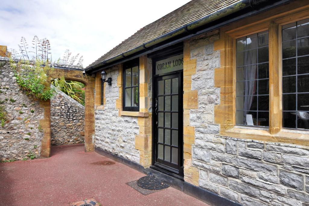 un antiguo edificio de piedra con una puerta y ventanas negras en Coram Lodge, en Lyme Regis
