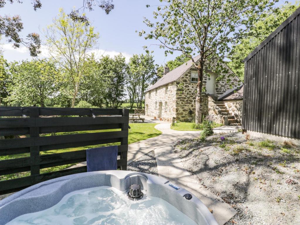 a bath tub in a yard next to a fence at Stabla in Pwllheli