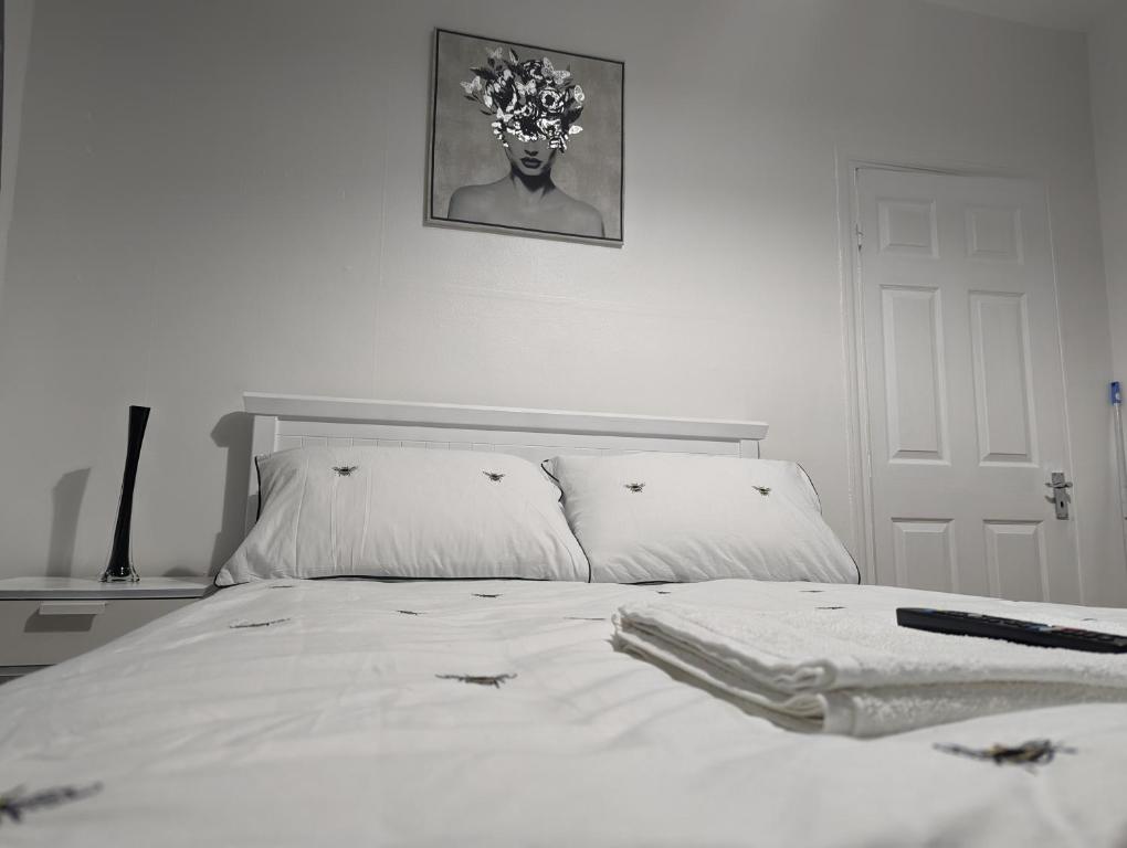 a bed with white sheets and a picture on the wall at The Saxon Rooms in Barking