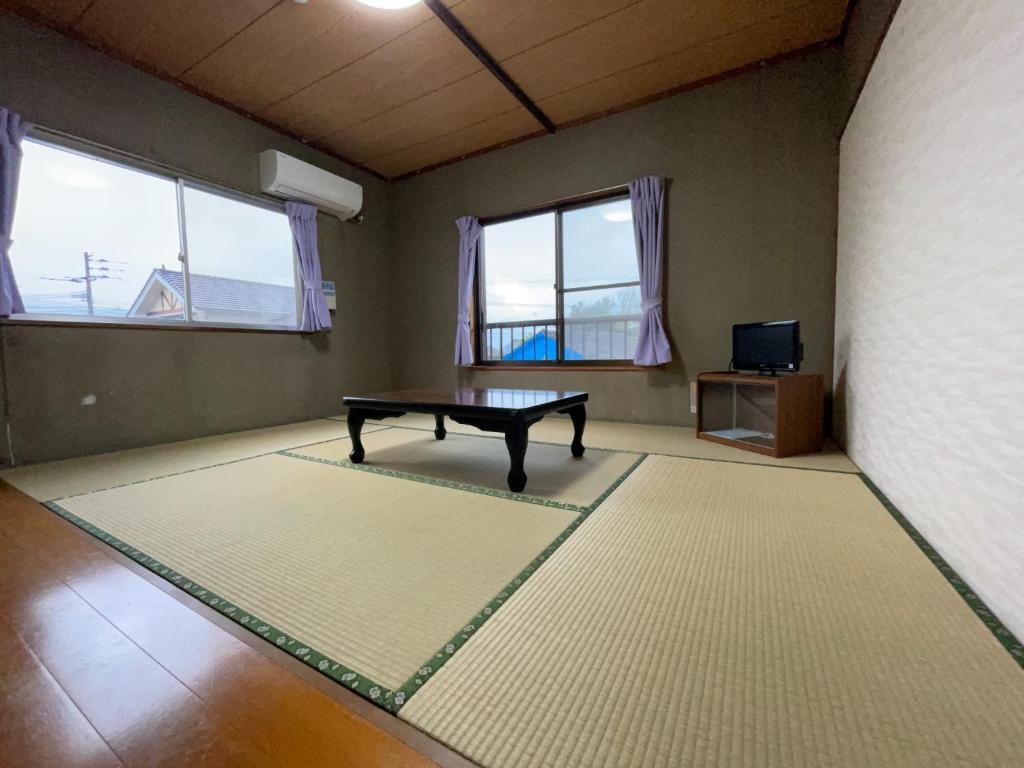 Zimmer mit einer Tischtennisplatte und 2 Fenstern in der Unterkunft Ryokan Warajisha - Vacation STAY 62566v in Goto