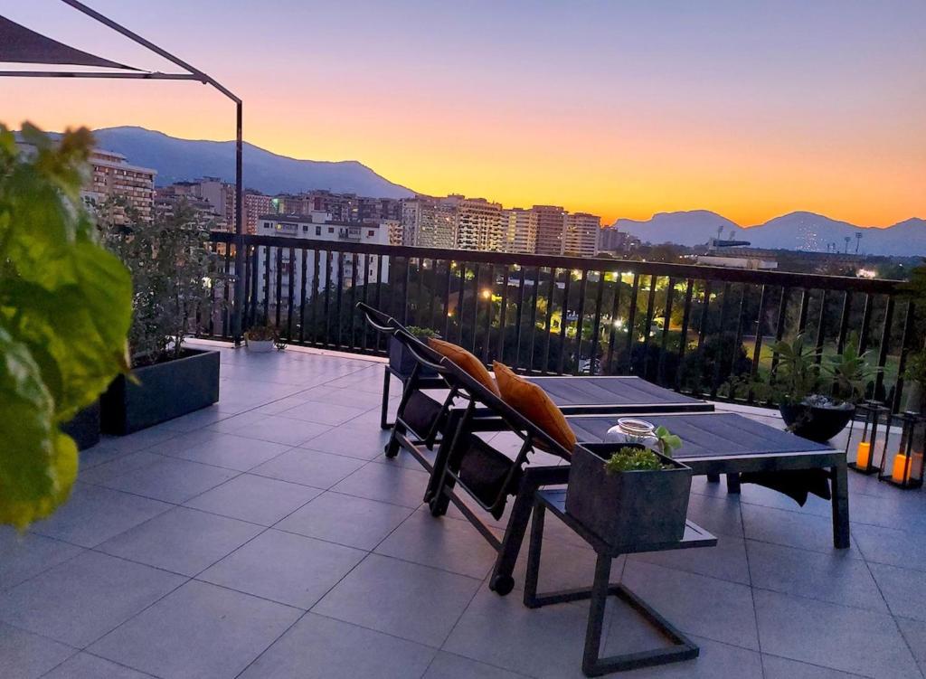 een tafel en stoelen op een balkon met uitzicht op de zonsondergang bij Gebel Grin in Palermo
