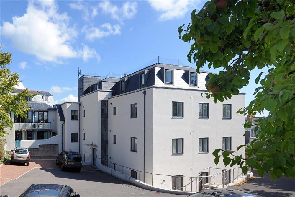 Un gran edificio blanco con coches aparcados en un estacionamiento. en The Lower Deck, en Lyme Regis
