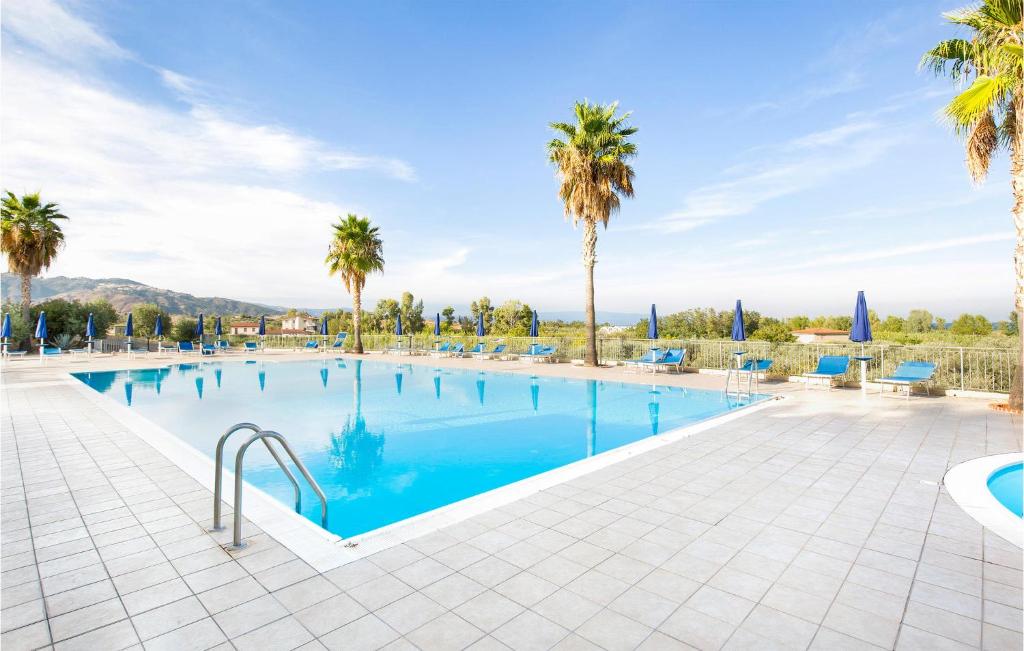 uma grande piscina com palmeiras e um céu azul em Villa 27 em Badolato