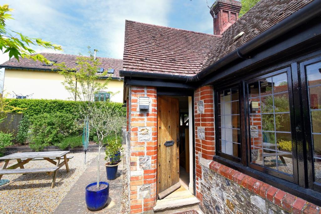 a brick house with a wooden door and a picnic table at Yard Cottage in Lyme Regis