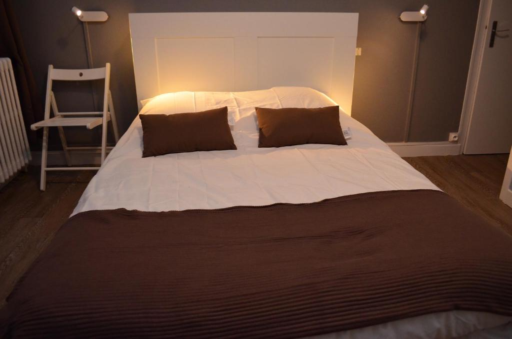 a large white bed with two pillows and a chair at Auberge du Lac in Marcilly-sur-Tille