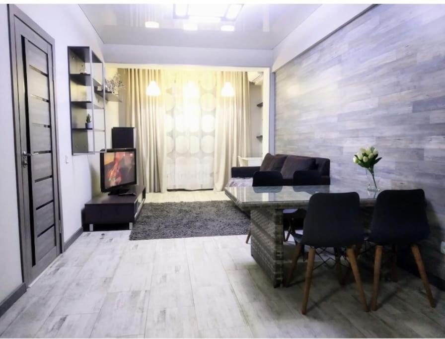 ein Wohnzimmer mit einem Sofa, einem Tisch und einem TV in der Unterkunft Прекрасная квартитира в г. Алматы in Almaty