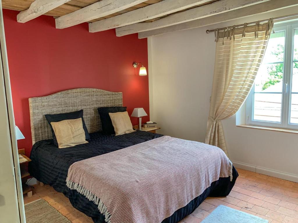 - une chambre avec un lit et un mur rouge dans l'établissement Fontevraud Les Chambres, à Fontevraud-l'Abbaye