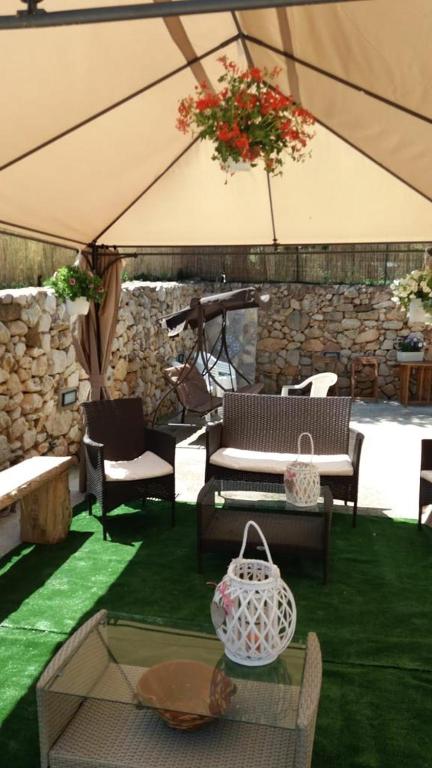 a patio with chairs and tables and a large umbrella at appartamento in villa splendente in Castellammare del Golfo