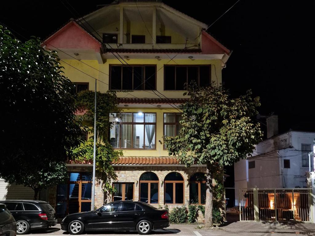 Czarny samochód zaparkowany przed żółtym budynkiem w obiekcie Hotel Restaurant Savoja w mieście Pogradec