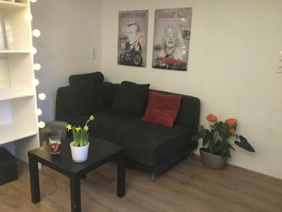 ein Wohnzimmer mit einem schwarzen Sofa und einem Tisch in der Unterkunft Studio, 21 minutes by bus to downtown Amsterdam in Purmerend