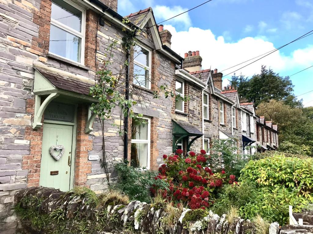 a row of brick houses with red flowers in front at Wenallt in Caernarfon