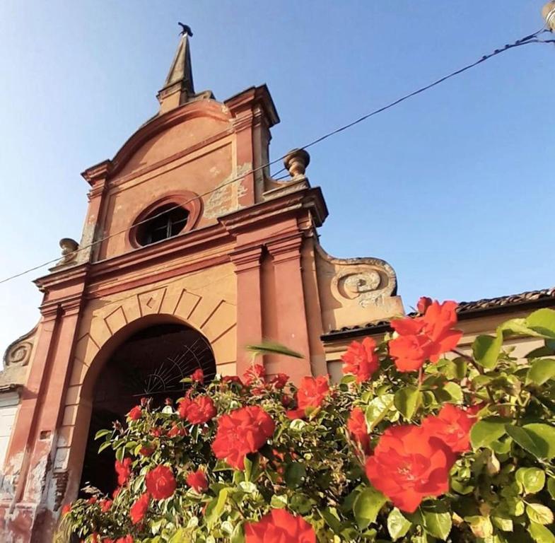un edificio con una torre del reloj con flores rojas en Il Corvo Viaggiatore, en Solarolo Monasterolo