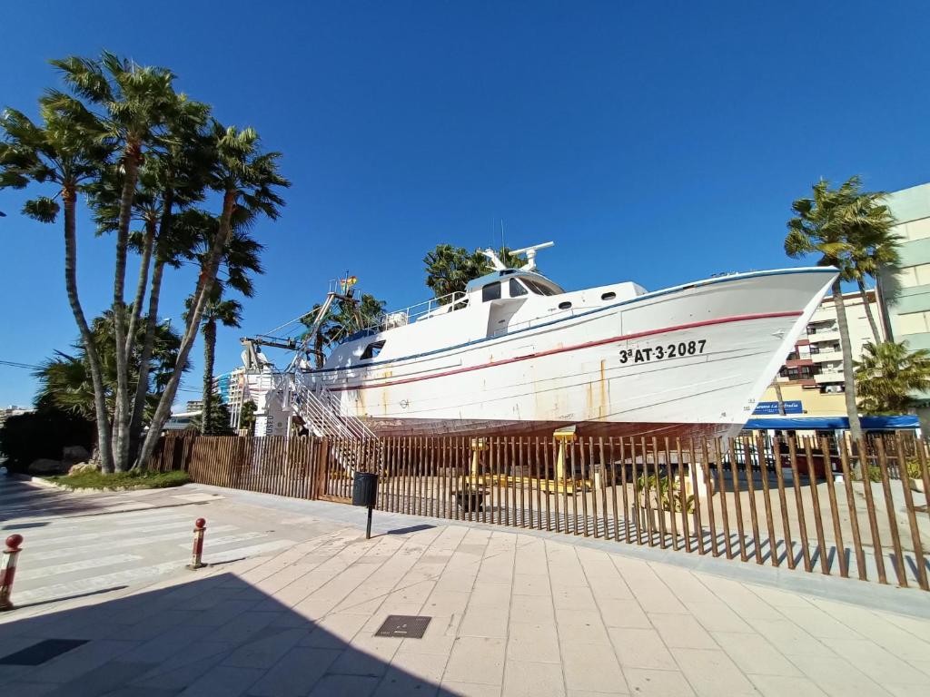 a large white boat parked next to a fence at La Cubana II con Aire Acondicionado in Santa Pola