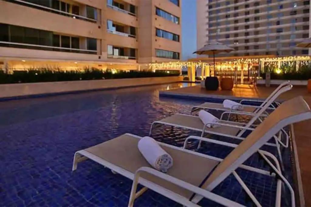 a pool with lounge chairs next to a building at Flat Apart America Campos in Campos dos Goytacazes