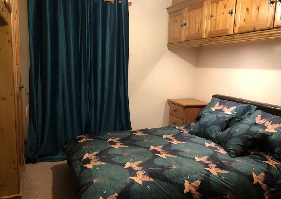 a bedroom with a bed with a green comforter with leaves at Lovely one-bed condo with free parking on premises in Sunderland