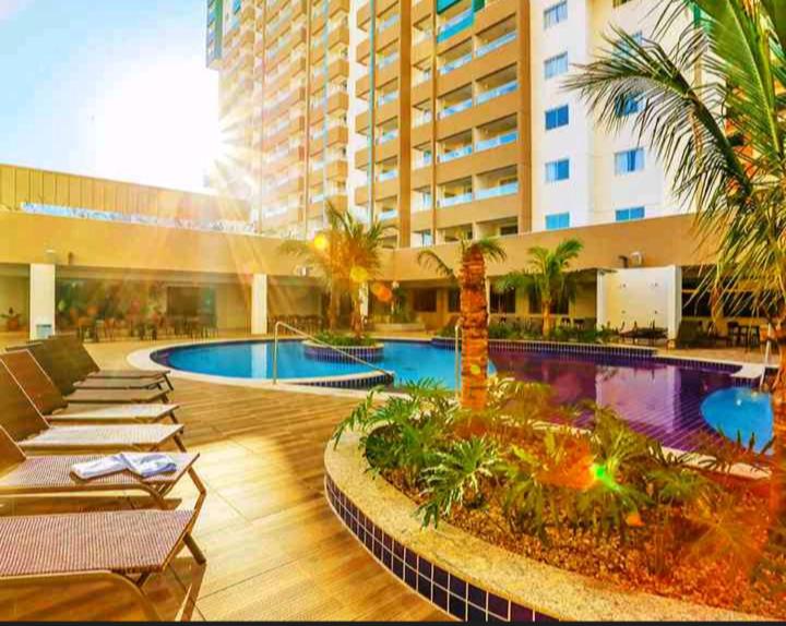 a hotel with a pool and palm trees and a building at Olímpia Park Resort-frente Thermas Laranjais-apt 5 p in Olímpia